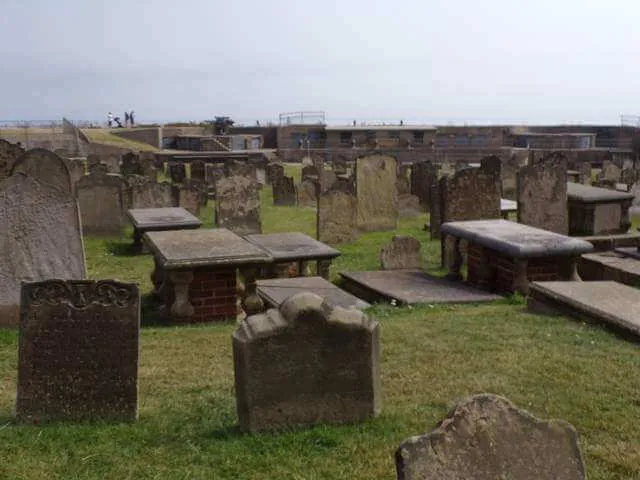Foto um - O cemitério e uma família com um carrinho de bebê podem ser vistos ao fundo.