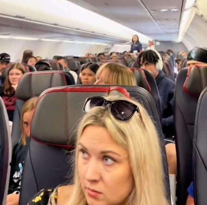 Os passageiros viraram a cabeça quando ela apareceu apontando para o fundo do avião enquanto falava sobre um cara que não era real.