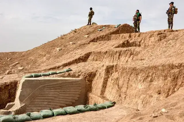 As forças de segurança iraquianas montam guarda no local onde o lamassu foi escavado novamente por uma equipe conjunta iraquiano-francesa.